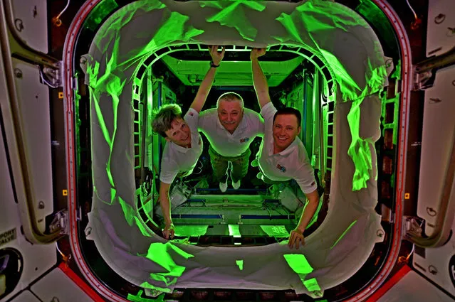 ISS crewmembers, from left, Peggy Whitson, Fyodor Yurchikhin and Jack Fischer pose for a group photo on July 16, 2017. “We decided to play with lights and make our crew picture. Remember black light bowling and roller rinks in the 80s? It's like that – only in space”, said Fischer. (Photo by Jack Fischer/NASA)