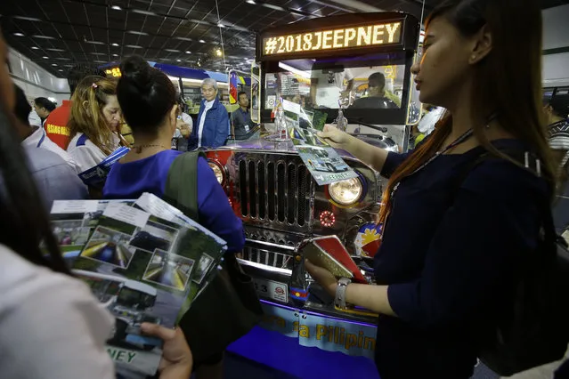 In this October 12, 2017, photo, visitors look at a Euro 4 emission compliant passenger jeep on display at an exhibit in Manila, Philippines. (Photo by Aaron Favila/AP Photo)