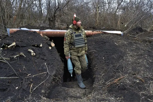 A Ukrainian soldier carries mortar shells before firing towards Russian positions near Bakhmut, Donetsk region, Ukraine, Thursday, December 22, 2022. (Photo by Libkos/AP Photo)