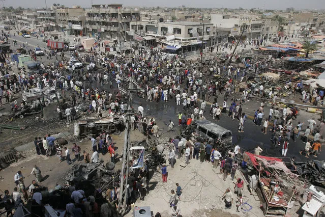 Hundreds of locals gather around the scene of a massive car bomb attack, on July 1, 2006, in the Sadr City area of Baghdad. A car bomb exploded in the morning outside of a popular Baghdad market killing 45 and wounding 41, while 14 vehicles and 22 shops and stalls were destroyed, said police. (Photo by Mohammed Hato/AP Photo/The Atlantic)