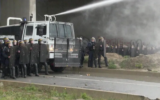 In this grab taken from video, french police spray protester using a water cannon, during a demonstration in Calais, France, Saturday, October 1, 2016. French police have fired tear gas and water cannons on protesters defending migrants in the northern city of Calais as the government prepares to shut down the city's notorious migrant camp. (Photo by AP Photo)