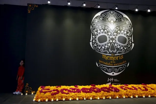 A child stands next to an altar for Day of the Dead in memory of Mexico's killed and disappeared journalists at the Memory and Tolerance Museum in Mexico City October 29, 2015. (Photo by Carlos Jasso/Reuters)