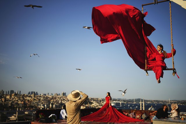 Tourists take photos in an open-air studio with a view of the Bosphorus in Istanbul, Turkey, Saturday, July 19, 2025. (Photo by Emrah Gurel/AP Photo)