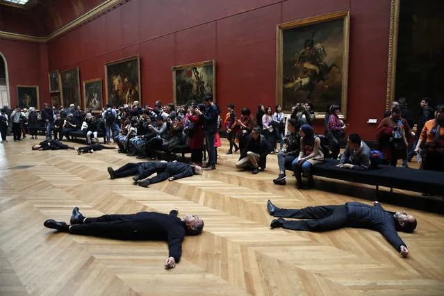 Activists lie on the floor inside the Louvre museum, as they stage a protest trying to call attention to migration driven by climate change, and notably to criticize activities of French oil giant Total, a prominent sponsor of Louvre activities, in Paris, Monday, March 12, 2018. (Photo by Christophe Ena/AP Photo)