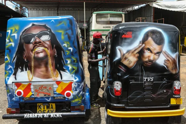 A mechanic (C) stands between two tuk-tuk painted with graffiti portraits of musicians as he repairs them at a garage in Thika, Kenya, 22 March 2018. (Photo by Daniel Irungu/EPA/EFE)