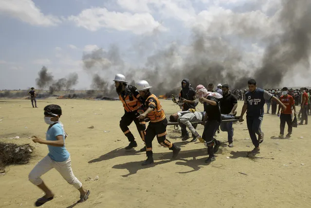 Palestinian medics and protesters evacuate a wounded youth during a protest at the Gaza Strip's border with Israel, east of Khan Younis, Gaza Strip, Monday, May 14, 2018. Thousands of Palestinians are protesting near Gaza's border with Israel, as Israel prepared for the festive inauguration of a new U.S. Embassy in contested Jerusalem. (Photo by Adel Hana/AP Photo)