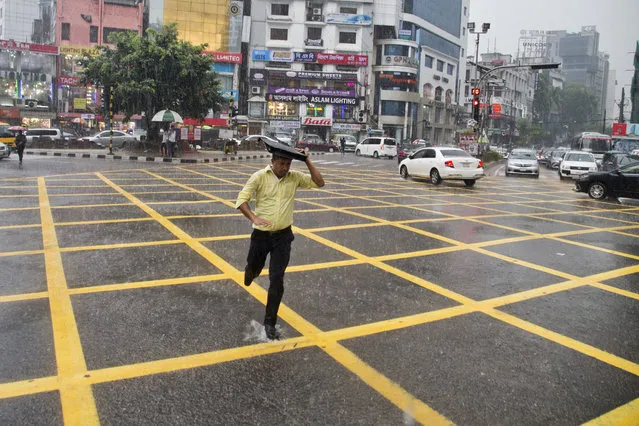 A Bangladeshi man runs across a street in the rain in Dhaka, Bangladesh, Tuesday, May 22, 2018. Monsoon season in Bangladesh begins in June. (Photo by A.M. Ahad/AP Photo)