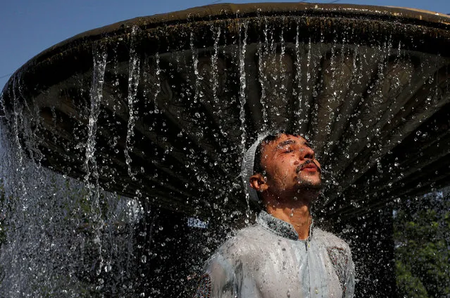 A man cools off from the heatwave, as he takes a shower at a water fountain along a road in Karachi, Pakistan May 25, 2018. The heatwave coincides with the beginning of Ramadan, when millions of devout Pakistanis abstain from food and drink from sunrise to sunset. (Photo by Akhtar Soomro/Reuters)