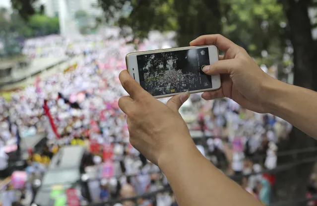 A man uses his smartphone to take photos during a rally against Jakarta Governor Basuki Tjahaja Purnama in Jakarta, Indonesia, Friday, November 4, 2016. Tens of thousands of hard-line Muslims marched Friday on the center of the Indonesian capital to demand the arrest of the minority-Christian governor for alleged blasphemy. (Photo by Tatan Syuflana/AP Photo)