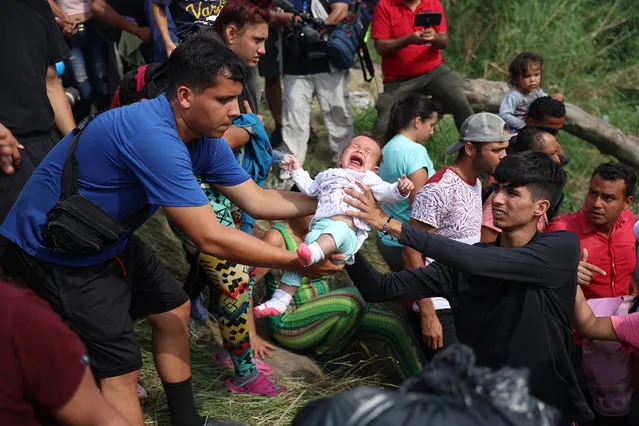 A baby is passed between people as migrants make their way into the Rio Grande as they cross to enter the United States on May 11, 2023 in Matamoros, Mexico. A surge of migrants is expected with the end of the U.S. government's Covid-era Title 42 policy, which for the past three years has allowed for the quick expulsion of irregular migrants entering the country. (Photo by Joe Raedle/Getty Images)
