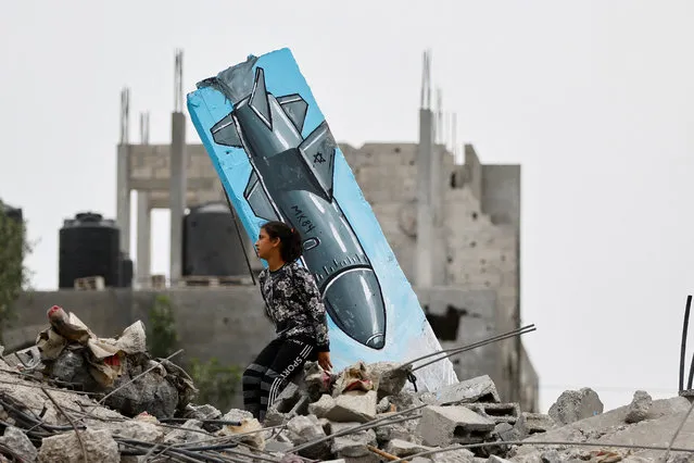 A Palestinian girl sits on the remains of a destroyed house, next to a graffiti of a missile drawn by Hussein Abu Sadeq, on houses destroyed by Israel in recent Israeli-Gaza fighting, in Deir Al-Balah, central Gaza Strip on June 8, 2023. (Photo by Ibraheem Abu Mustafa/Reuters)