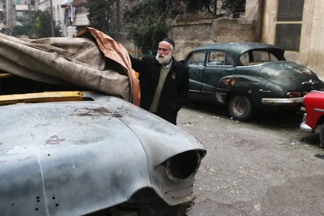 Mohamed Badr al-Din removes a cover from one of his cars that he says belonged to former Syrian President Adib Shishakli, along a street where he keeps the cars, in the al-Shaar neighborhood of Aleppo January 31, 2015. (Photo by Abdalrhman Ismail/Reuters)