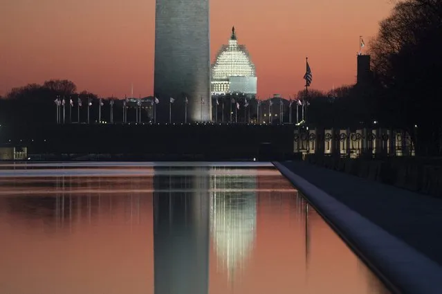 The sun begins to rise on the last day of the year, with the base of the Washington Monument and US Capitol Building reflected in the Lincoln Memorial Reflecting Pool, in Washington DC, USA, 31 December 2014. (Photo by Michael Reynolds/EPA)