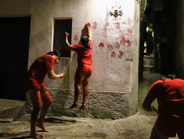 Men know as “Vattienti”, the faithful penitents scourging their thighs as part of the “Vattienti” religious ritual of flagellation during Holy Week, print their blood-stained palm on a house as they perform the ritual overnight on April 15, 2022 in Verbicaro, Calabria, southern Italy. (Photo by Gianluca Chininea/AFP Photo)