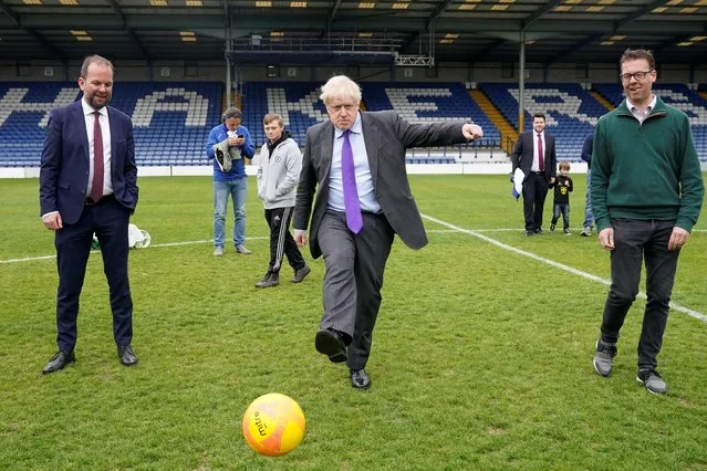 Britain's Prime Minister Boris Johnson shoots a ball during a visit to the football club Bury FC at their ground in Gigg Lane, Bury, Greater Manchester, on April 25, 2022. (Photo by Danny Lawson/Pool via AFP Photo)