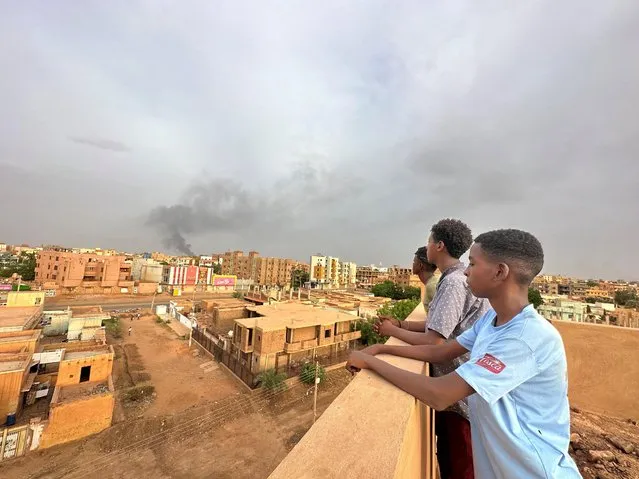 People watch as smoke rises during clashes between the army and the paramilitary Rapid Support Forces (RSF), in Omdurman, Sudan on July 4, 2023. (Photo by Mostafa Saied/Reuters)
