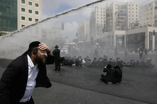 Ultra-Orthodox Jews, demonstrating against the annual Gay Parade, are sprayed with water cannons by Israeli security forces in Jerusalem on August 2, 2018. The 17th edition of Gay Pride in the holy city, was held under heavy police surveillance, the murder of a 16-year-old girl, stabbed to death by an ultra-Orthodox Jew during the 2015 parade, remaining very present in the minds. (Photo by Menahem Kahana/AFP Photo)