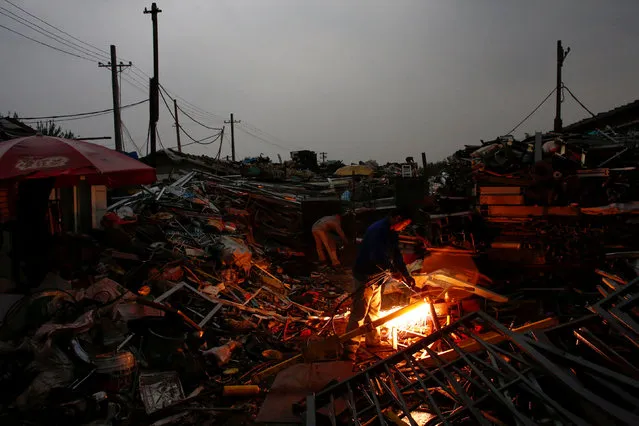 A worker cuts metal at a scrap metal stall at a recycling yard at the edge of Beijing, China, October 20, 2016. (Photo by Thomas Peter/Reuters)