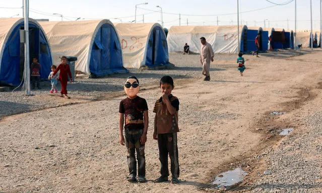 An Iraqi displaced boy (L) wears a mask depicting Korean pop star Park Jae-sang as he stands with a friend at Jadaa refugees camp near Qayyarah city, some 40 km southern Mosul, Iraq, 17 November 2016. According to a local official in Jadaa camp, the camp which was opened after the beginning of the military operation to liberation of Mosul city, is currently hosting around ten thousand people who fled from many villages near Mosul due to the fighting between the Iraqi forces and Islamic State (IS) group. (Photo by Ahmed Jalil/EPA)