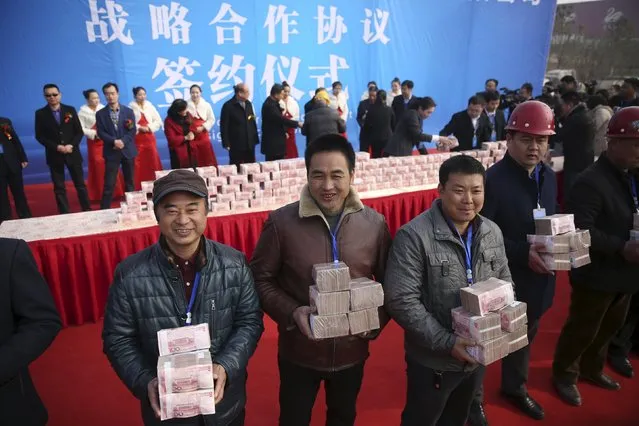 Construction workers smile as they hold their salaries in bundles of 100 yuan banknotes during a ceremony held by a real estate developer, in Luoyang, Henan province, China, January 9, 2016. (Photo by Reuters/Stringer)