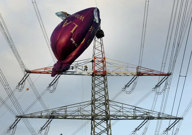A hot air balloon sits on top of a high-voltage power line in Bottrop, Monday, October 1, 2018 after it collided the evening before. Six passengers were rescued from a height of 65 meters (210 feet). (Photo by Roland Weihrauch/DPA via AP Photo)