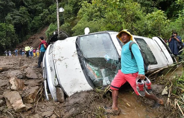 A man walks in front a car dragged by flooding in Locotal, between Cochabamba and Santa Cruz, Bolivia, December 8, 2016. (Photo by Reuters/APG Agency)