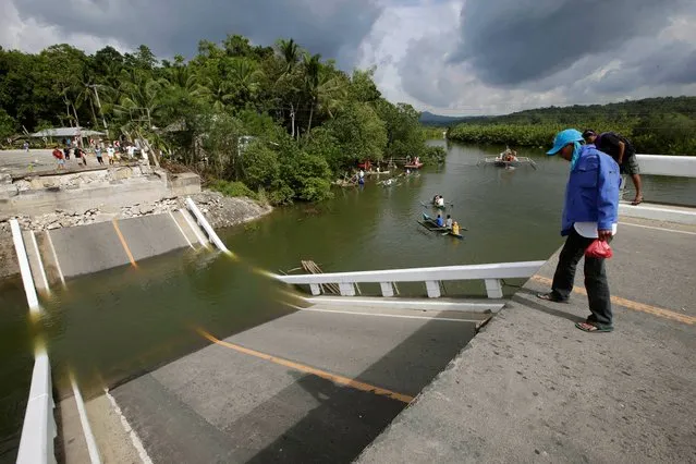 Residents look at a bridge which collapsed during Tuesday's quake as commuters use small boats to cross the water in Cortes township, Bohol province in central Philippines Wednesday October 16, 2013. The 7.2-magnitude quake which hit Bohol and Cebu provinces Tuesday morning damaged churches, buildings and homes and caused multiple deaths across the central region. (Photo by Bullit Marquez/AP Photo)