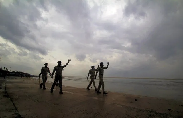 Policemen ask people to move to cyclone shelters as they patrol a beach in Balasore district in Odisha, India, Tuesday, May 25, 2021. Tens of thousands of people were evacuated Tuesday in low-lying areas of two Indian states and moved to cyclone shelters to escape a powerful storm barreling toward the eastern coast. (Photo by AP Photo/Stringer)
