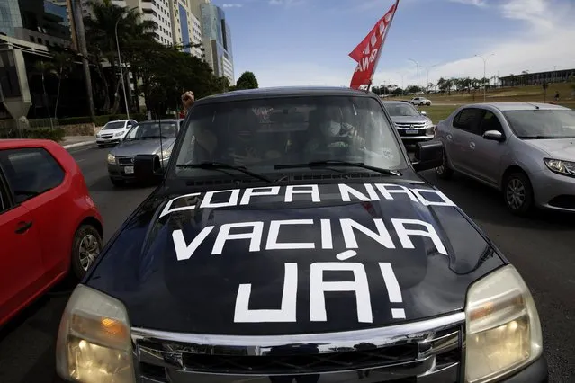 Protesters drive their car with a sign reading in Portuguese “Copa No, Vaccines Now” to protest the holding of Copa America in Brasilia, Brazil, Sunday, June 6, 2021. Brazil accepted hosting the South American soccer tournament after the original co-hosts were dropped: Colombia due to political protests and Argentina for rising of COVID-19 cases. (Photo by Eraldo Peres/AP Photo)