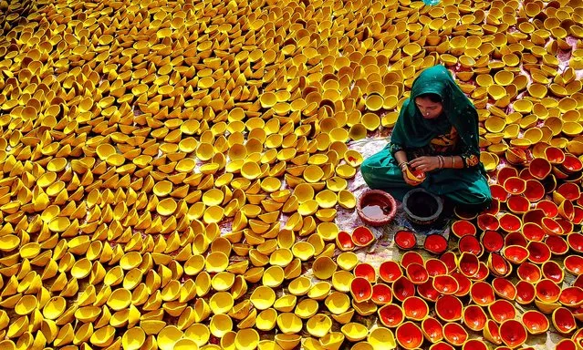 A potter paints earthen lamps ahead of Diwali, or the Hindu festival of lights, in Amritsar, India, on Oktober 30, 2013. Hindus light lamps, wear new clothes, exchange sweets and gifts and pray to goddess Lakshmi during the festival which will be celebrated on November 3. (Photo by Prabhjot Gill/Associated Press)