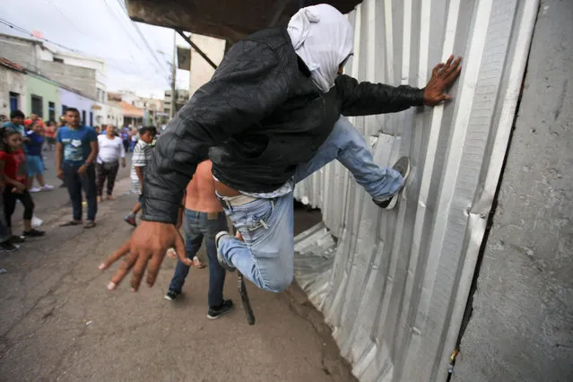 A man jump kicks a sheet metal wall during a protest by street vendors in Tegucigalpa, Honduras, 20 December 2016. Honduran police evicted dozens of street vendors after they occupied several streets to sell Christmas items in the downtown area of Tegucigalpa. (Photo by Gustavo Amador/EPA)