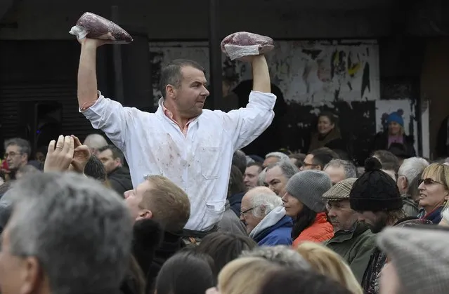 A butcher holds up cuts of meat during a Christmas eve auction in Smithfield market, London, Britain December 24, 2016. (Photo by Toby Melville/Reuters)