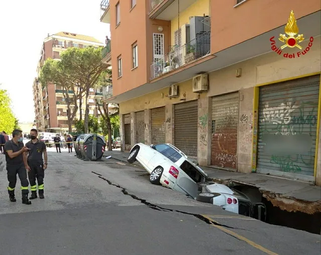 Cars are seen stuck sideways in a huge hole that has opened up next to a Rome apartment building, in Rome, Italy, May 25, 2021. (Photo by Vigili Del Fuoco/Handout via Reuters)
