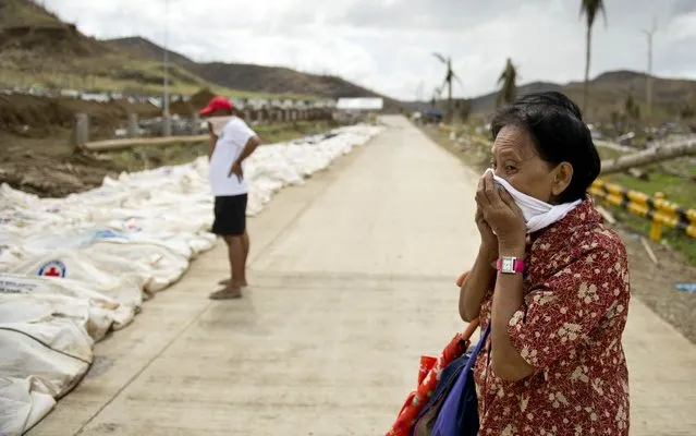 A woman covers her nose and mouth as she stopped to look at the body bags containing the remains of some 170 dead collected from the rubble at the “Cemetery of the hills”, one of three mass burial sites where they so far have received one thousand typhoon victims in Tacloban on November 19, 2013. Philippine President Benigno Aquino blamed the slow response to the ravages of Typhoon Haiyan on the total collapse of local government in the face of the storm's unprecedented destructive power. (Photo by Odd Andersen/AFP Photo)