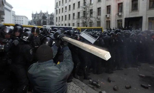 A man holds a stick as protesters try to break through police lines near the presidential administration building during a rally held by supporters of EU integration in Kiev, December 1, 2013. Hundreds of thousands of Ukrainians shouting “Down with the Gang!” rallied on Sunday against President Viktor Yanukovich's U-turn on Europe and some used a building excavator to try to break through police lines at his headquarters. (Photo by Vasily Fedosenko/Reuters)