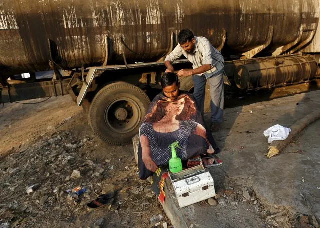 A truck driver gets a haircut from a roadside barber at an industrial area in Mumbai, India, January 27, 2016. (Photo by Danish Siddiqui/Reuters)