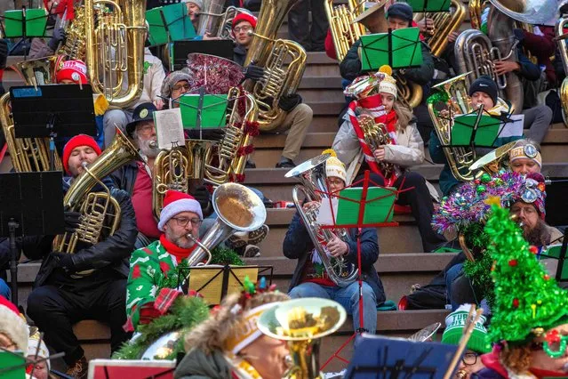Musicians perform holiday songs during the 50th anniversary of “Tuba Christmas” at Downtown Crossing in Boston, Massachusetts, on November 25, 2023. The event, in its 50th year nationwide, has been performed in the city of Boston since 1986. Holiday favorites are played on various instruments in the tuba family, from euphonias to sousaphones. (Photo by Joseph Prezioso/AFP Photo)