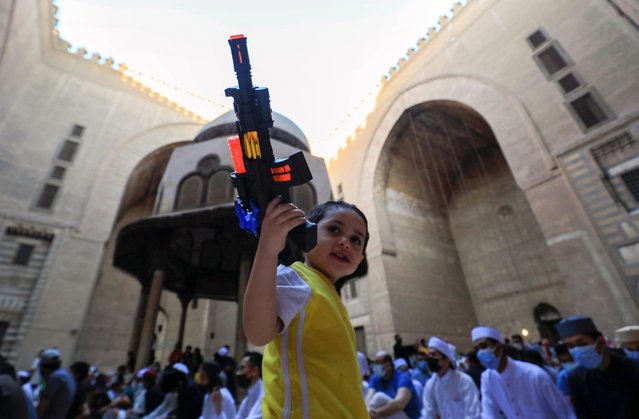 A boy plays with a toy gun in front of Muslim worshippers attending Eid al-Fitr prayer to mark the end of the holy fasting month of Ramadan, inside Al Sultan Hassan mosque, amid the coronavirus disease (COVID-19) pandemic, in old Cairo, Egypt on May 13, 2021. (Photo by Amr Abdallah Dalsh/Reuters)