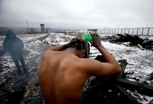 In this Saturday, January 14, 2017 photo, a migrant washes himself outside a crumbling warehouse that has served as a makeshift shelter in Belgrade, Serbia. It was a week in frigid hell for hundreds of migrants squatting in an abandoned warehouse in the Serbian capital of Belgrade while trying to move on toward Western Europe. When the weather suddenly turned nasty it sent temperatures plummeting way below zero and cold wind started to blow pushing into every corner of make-shift migrant shelter. (Photo by Darko Vojinovic/AP Photo)