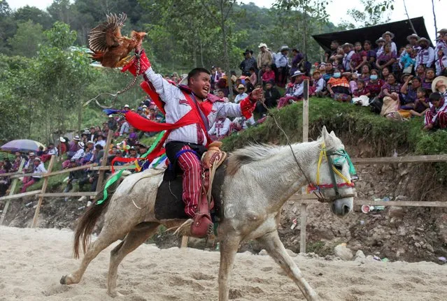 A Guatemalan Indigenous man rides during a horse race, featuring riders dressed in traditional costumes, as he celebrate the traditional festivities, at the village of Todos Santos Cuchumatan, Guatemala on November 1, 2022. (Photo by Sandra Sebastian/Reuters)