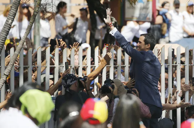Venezuela’s self-proclaimed interim president Juan Guiado greets the crowd during an event to swear in nurses, doctors, professionals and others, as the group that will help with the arrival and distribution of humanitarian aid in Venezuela, in Caracas, Venezuela, Saturday, February 16, 2019. The U.S. Air Force has begun flying tons of aid to a Colombian town on the Venezuelan border as part of an effort meant to undermine socialist President Nicolas Maduro. The first of three C-17 cargo planes has flown from Homestead Air Reserve Base in Florida and landed in the town of Cucuta. (Photo by Ariana Cubillos/AP Photo)