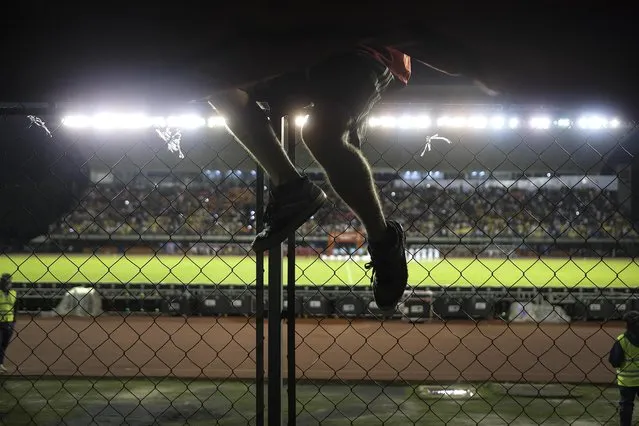 A member of the Caracas FC fan club who call themselves The Red Demons, climbs a fence in the stands during the qualifying World Cup Qatar 2022 qualifying soccer match between Venezuela and Argentina at the UCV Olympic Stadium in Caracas, Venezuela, Thursday, September 2, 2021. The stadium is open to fans for first time since the COVID-19 lockdown started in March 2020. (Photo by Matias Delacroix/AP Photo)