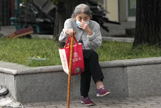 An elderly resident wears a mask while waiting for a ride on a sidewalk in Beijing, China, Thursday, September 16, 2021. (Photo by Ng Han Guan/AP Photo)