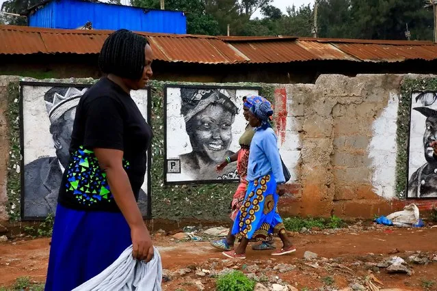 Women walk past wall art murals created by youths from The Rockers movement of Kibera Slum on January 10, 2024 in Nairobi, Kenya. In the heart of Kibera Slum, a youth movement named The Rockers is planting seeds of change by creating murals and building social amenities through recycling. (Photo by Donwilson Odhiambo/Getty Images)