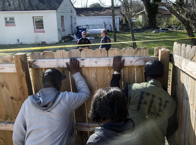 Onlookers peer through a fence as Raleigh police officers work the scene of a police-involved shooting near the intersection of Bragg and South East Streets in Raleigh, NC, USA, on Monday, February 29, 2016. (Photo by Travis Long/Raleigh News & Observer/TNS/ABACAPRESS.COM)