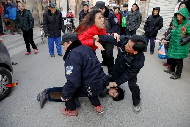 A member of a local public security force holds a seized hatchet as he and others try to overpower a couple at the Picun village, home to thousands of migrant workers in suburbs of Beijing, China January 24, 2017. Brandishing a hatchet, He Dan charged at local public security personnel as they were arguing and scuffling with his wife Zhang Shaolei over the couple's vehicle parked in the village's main street. The couple said security personnel asked them to pay a 500 RMB ($73) fine as they were getting ready to leave to their hometown for the Spring Festival. (Photo by Damir Sagolj/Reuters)