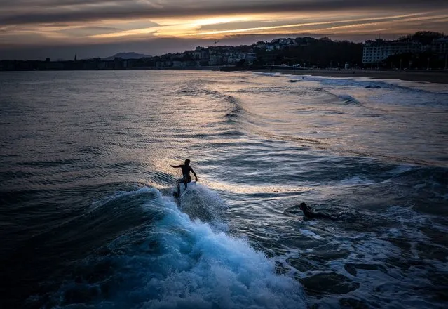 Two women surf at San Sebastian, Basque Country, Spain, 30 January 2024. Spain continues in a period of high pressure which has settled the weather conditions with high temperatures during the winter season. (Photo by Javier Etxezarreta/EPA/EFE)