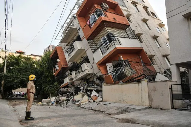 A fire force personnel watches as a multi-storey apartment building collapsed without any casualties reported, in Bangalore on October 7, 2021. (Photo by Manjunath Kiran/AFP Photo)