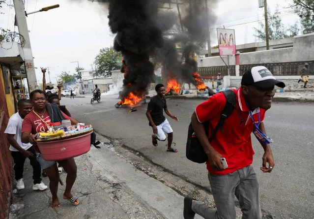 People react as they walk near a burning barricade set up in protest against the government, calling for the resignation of Prime Minister Ariel Henry, in Port-au-Prince, Haiti on February 5, 2024. (Photo by Ralph Tedy Erol/Reuters)