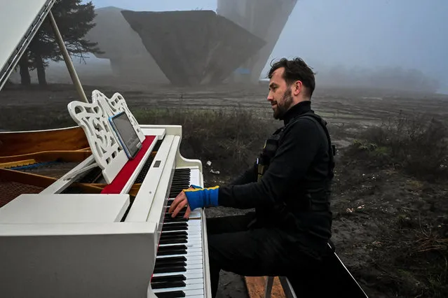 This photograph taken on December 13, 2022, shows Lithuanian pianist Darius Majintas, playing music by Ukrainian composer Valentin Sylvestrov, on Kremyanets mountain in Izyum, Kharkiv region, amid the Russian invasion of Ukraine. (Photo by Sergey Bobok/AFP Photo)